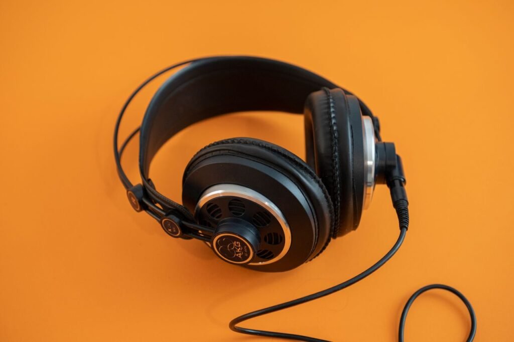 Studio shot of black headphones on a vibrant orange background highlighting electronic accessory design.