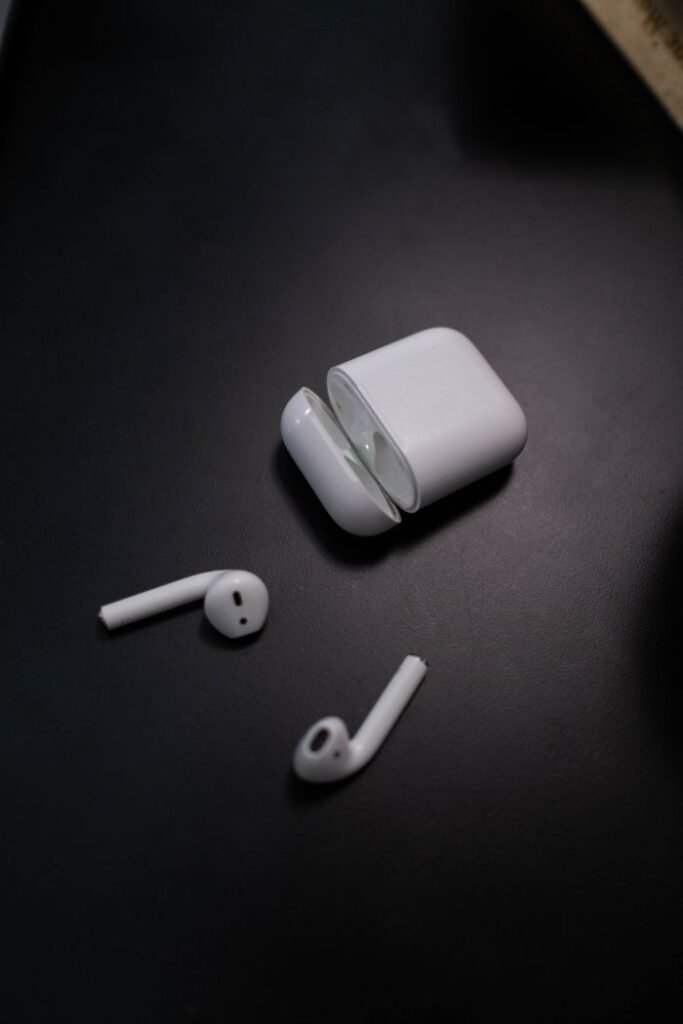 Close-up of wireless white earphones and case on a sleek black surface, highlighting modern technology.