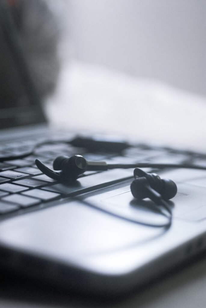 Black earphones resting on a laptop keyboard in soft focus. Ideal for tech and lifestyle themes.