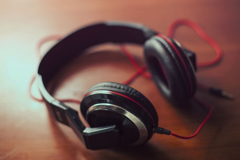 Close-up of red and black headphones on a wooden surface, ideal for music concepts.